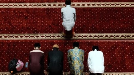 Muslim men performing prayer inside a mosque in Jakarta, Indonesia, captured from above.