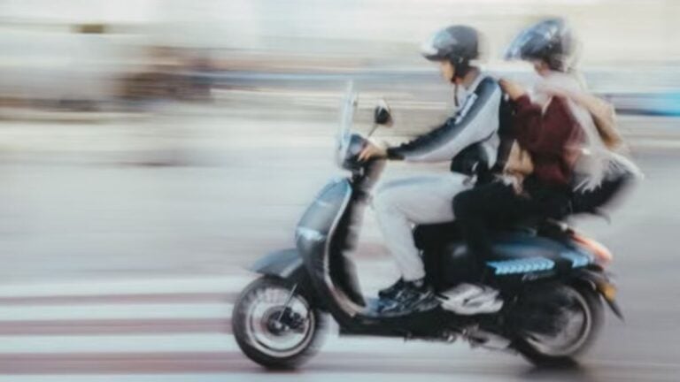 Motion-blurred image of two people riding a scooter through a city street in Rabat, Morocco.