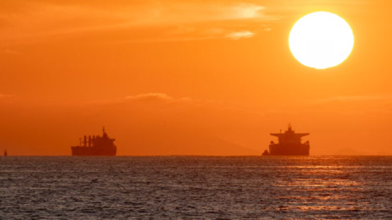 Oil tankers silhouetted against a vibrant sunset over the Pacific Ocean