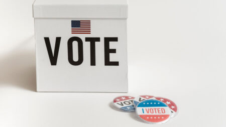 Lawsuit Claims DHS Voter Checks Could Wrongly Target Naturalized Americans White ballot box with USA flag and badges