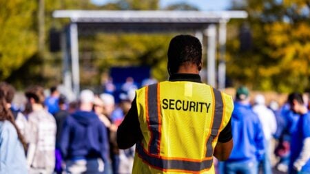 A security guard monitors a crowd at an outdoor event.