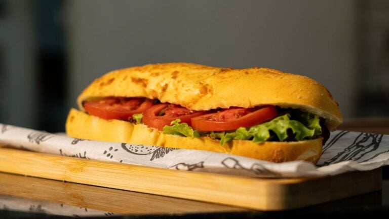 Sub sandwich with fresh tomatoes and lettuce on a wooden board.