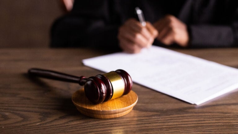 Judge Finally Stops Saying Racial Slur in Court After Years of Complaints A judge signing papers on a wooden desk