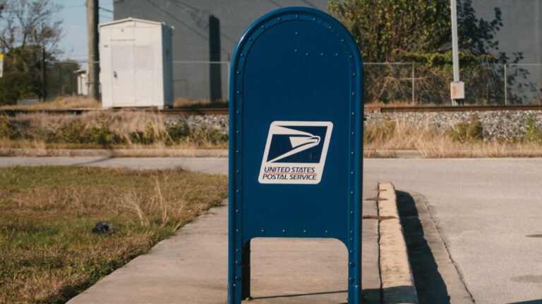Blue USPS mailbox on a sunny day in a suburban street scene