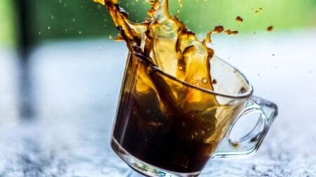 Capture of coffee splash in a transparent glass cup with a blurred background.