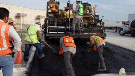 ‘Pot for Potholes’: Frustrated Tennessee Locals Push Alternative as $400 Million Road Shortfall Could Mean Higher Taxes Construction workers laying asphalt on a road with heavy machinery.