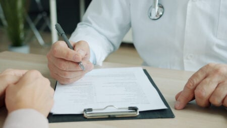 ‘When Are Americans Going To Say Enough Is Enough’: Federal Employee Blasts Soaring Health Insurance Costs, Calling Industry Becomes a ‘Complete Scam’ Close-up of doctor and patient reviewing medical documents during consultation