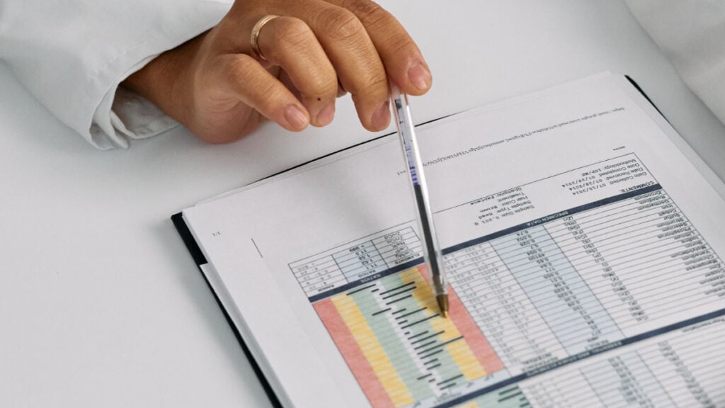 ‘I Feel Completely Violated’: North Carolina Woman Accuses Clinic of Letting Outside Company ‘Monetize’ Her Medical Diagnosis Doctor analyzing patient charts with a pen, focusing on data points for medical insights