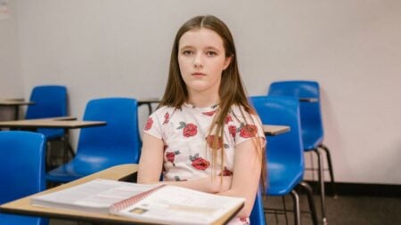 ‘I Walk in With Dread’: Texas Locals Outraged as Fort Worth Students Speak Out Against State-Imposed Classroom Changes A young girl sits alone in an empty classroom looking pensive and isolated.