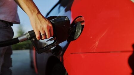 North Carolina Drivers Skeptical of Proposed 41-Cent Gas Tax Cut as Stations Aren’t Required to Pass On Savings: ‘Every Time I Go to the Tank It’s $100’ Close-up of a person refueling a red car at an outdoor gas station during the day.