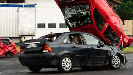 Illinois Driver Suddenly Smashes SUV Into Outdoor Dining Area After People Filming Hype Him Up: ‘And They’ll Give Him a Parking Ticket’ A thrilling car stunt crash with a red car flipped onto a black vehicle in an outdoor setting.