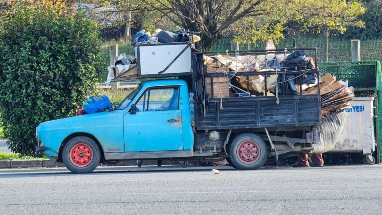 Florida Customer Refuses to Pay Junk Hauler, So He Dumps All Their Debris Right Back on the Driveway: ‘Driver Should Get a Medal’ Side view of a vintage blue truck loaded with recyclable waste on a sunny day.
