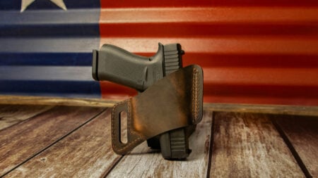 ‘We Can Take Guns on University Campuses’: Internet Mocks Texas Priorities Amid $900 Health Insurance Issue Handgun in holster with Texas flag behind it