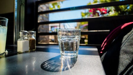 ‘That’s a Crazy Hill To Die On’: Philadelphia Cheesesteak Shop Refuses Free Water to Paying Customers But Sells Beer A glass of water placed on a sunlit table in an outdoor cafe setting with blurred greenery