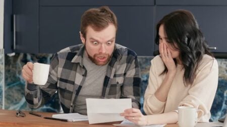 ‘And It’s Not Even Cold Yet’: Ohio Residents Sound Alarm Over Soaring Electricity Bills as Winter Approaches A worried couple reviewing financial documents at their kitchen table.