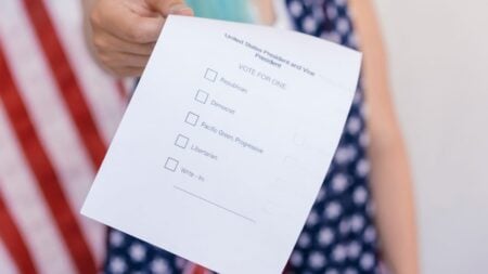 Close-up photo of a hand holding a US election voting ballot.